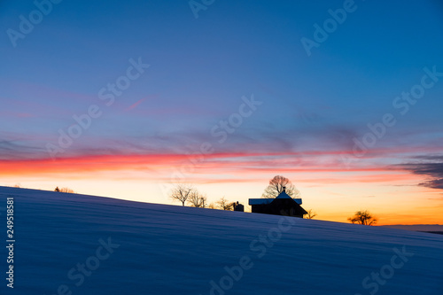 silhouette of a farm in Emmental at a winter sunset