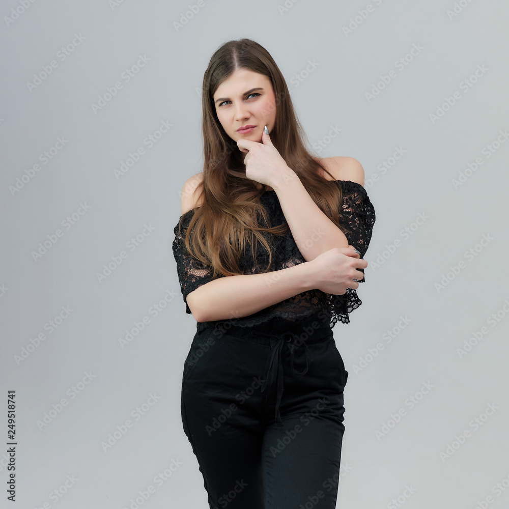 Concept portrait of a pretty beautiful brunette girl talking on a gray background in the studio standing Concept portrait of a pretty beautiful brunette girl talking on a gray background in the studio standing