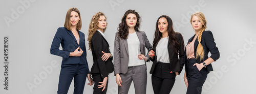beautiful successful women standing with hands in pockets isolated on grey