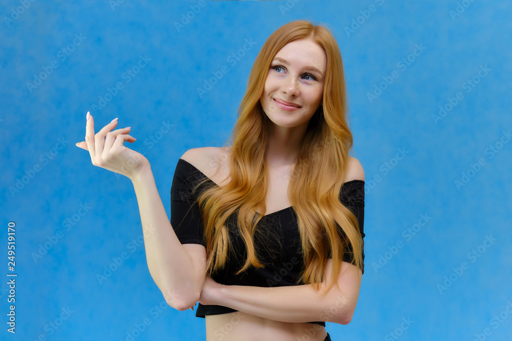 Concept portrait of a pretty beautiful red-haired girl talking on a blue background in the studio