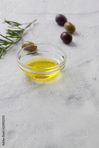 Olives and olive oil with herbs on a neutral background with limited depth of focus