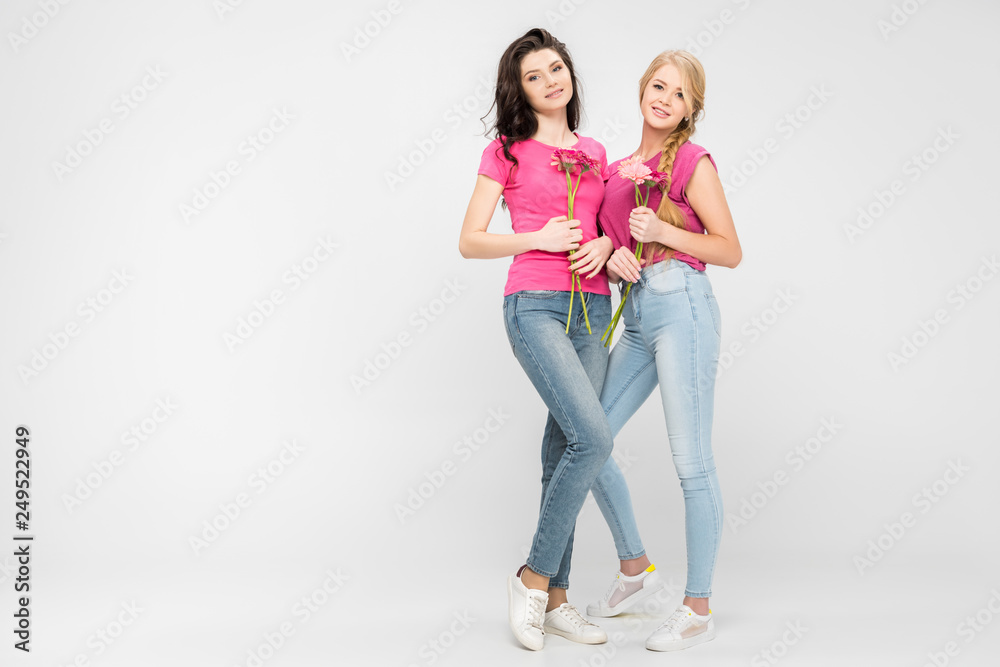 Obraz premium beautiful women holding flowers and standing on grey background