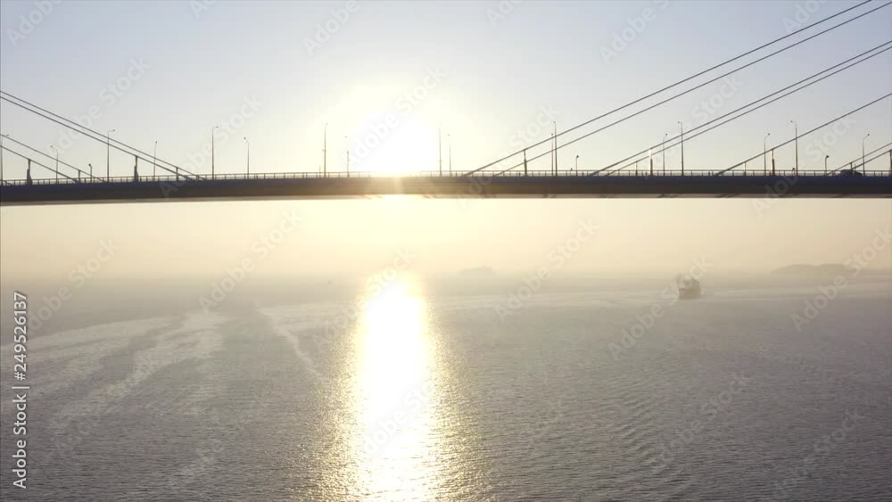 Flying sideways, aerial view of Russian bridge road with driving cars. Beautiful winter sunrise above the Eastern Bosphorus strait. Vladivostok, Russia Flying sideways, aerial view of Russian bridge road with driving cars. Beautiful winter sunrise above the Eastern Bosphorus strait. Vladivostok, Russia