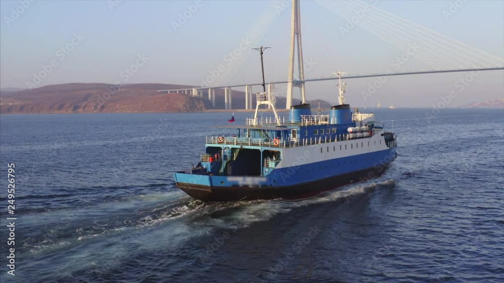 Aerial view of ferry sailing to Vadivostok along the Eastern Bosphorus strait under Russian bridge. Sunny day Aerial view of ferry sailing to Vadivostok along the Eastern Bosphorus strait under Russian bridge. Sunny day