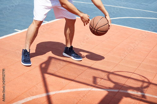 young asian adult practicing basketball skills on outdoor court