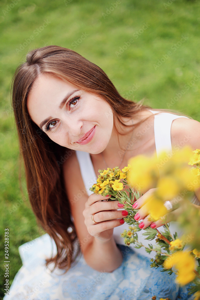 Portrait of a beautiful amazing girl with kind eyes, gentle smile, long curly hair. Young happy woman walking in the garden with flowers Portrait of a beautiful amazing girl with kind eyes, gentle smile, long curly hair. Young happy woman walking in the garden with flowers