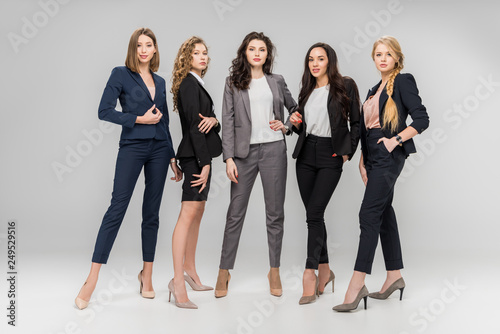 beautiful successful women standing with hands in pockets on grey background