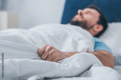 man lying in bed and holding blanket