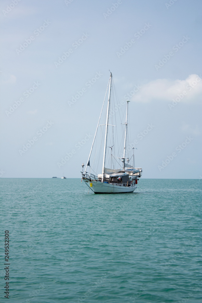 White sailboat swimming in the sea near the coast of Ko Samui island, Thailand