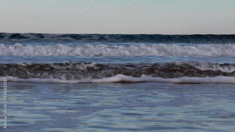 gentle, calm coastal waves of north east Scotland set against distant landscape with the light and colours of sunset during winter. gentle, calm coastal waves of north east Scotland set against distant landscape with the light and colours of sunset during winter.