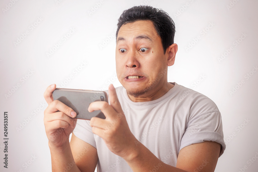 Funny Young Asian Guy Playing Games on Tablet Funny Young Asian Guy Playing Games on Tablet
