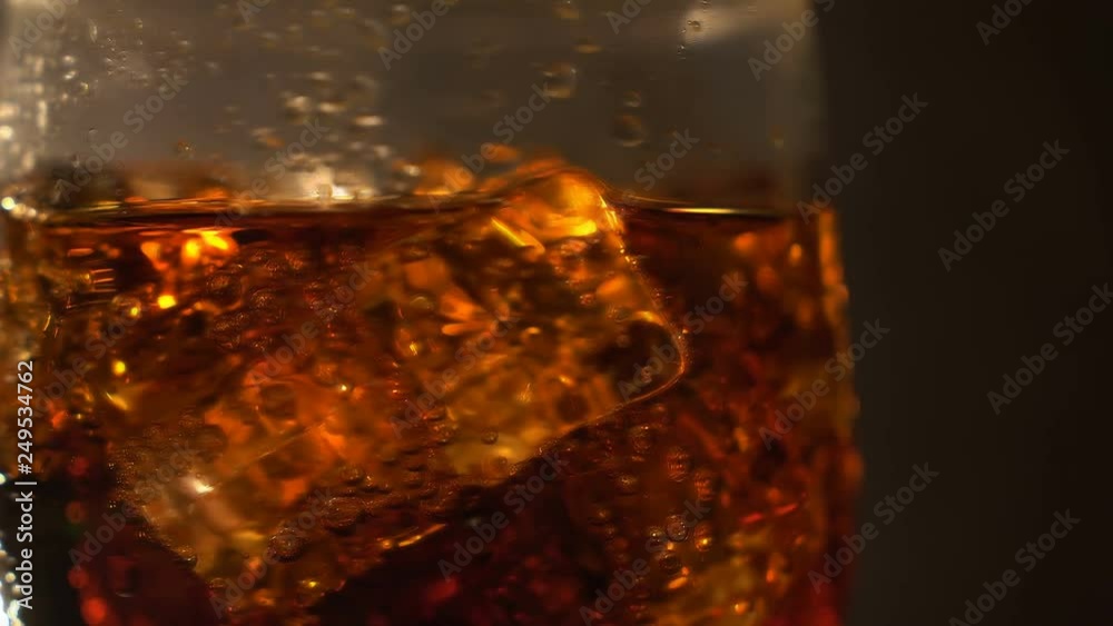 Cola in the glass with Ice cubes and bubbles rotating. Food background. Soda Close-up. Cola in the glass with Ice cubes and bubbles rotating. Food background. Soda Close-up.