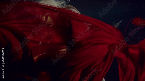Swimming underwater woman in a dark dress.
