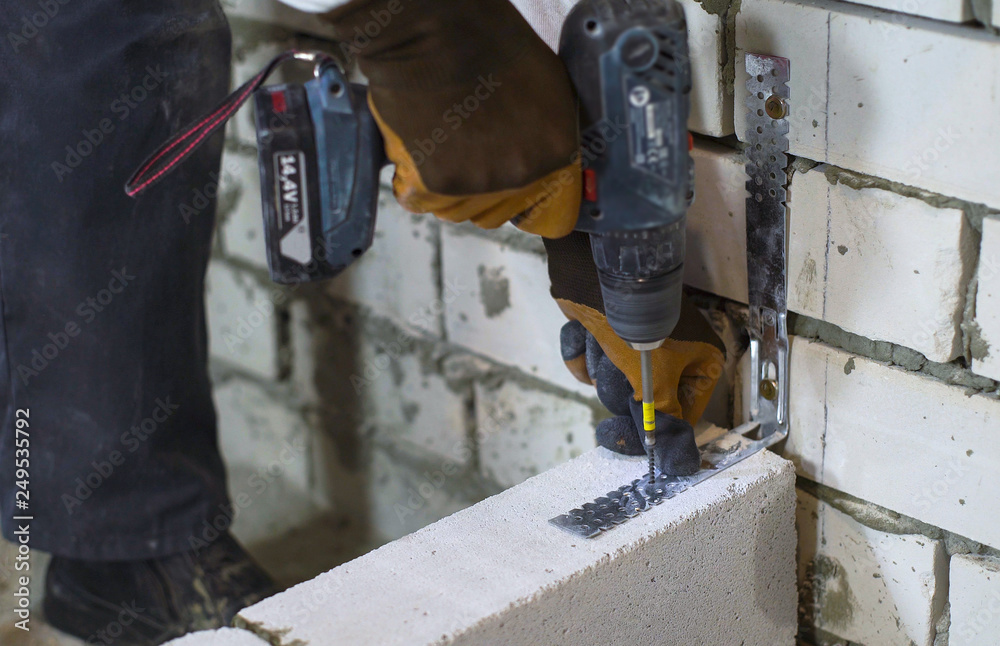 builder screwing joining clamp in aerated concrete block with electric drill builder screwing joining clamp in aerated concrete block with electric drill