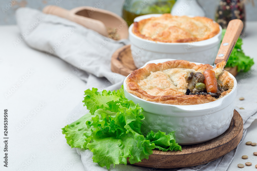 Vegetarian pot pie with lentil, mushroom, potato, carrot and green peas, covered with puff pastry, in baking dish, horizontal, copy space Vegetarian pot pie with lentil, mushroom, potato, carrot and green peas, covered with puff pastry, in baking dish, horizontal, copy space