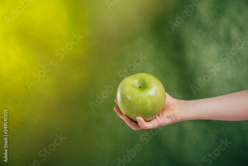 partial view of child hand with apple on blurred background, earth day concept © LIGHTFIELD STUDIOS