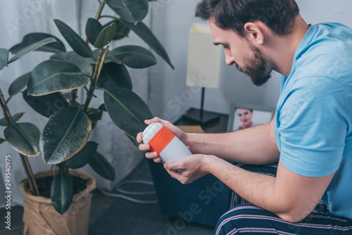 Obraz na plátně upset man sitting and looking at funeral urn at home