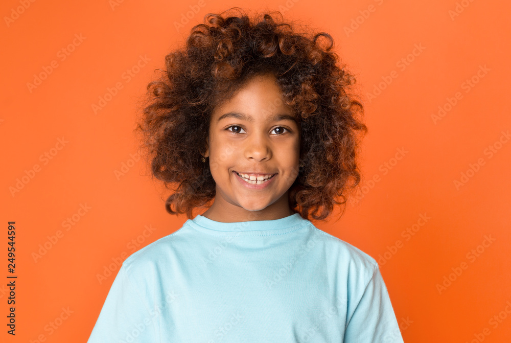 Portrait of adorable african-american child girl over orange background Portrait of adorable african-american child girl over orange background