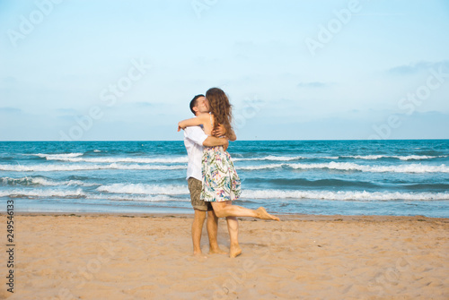 Euphoric young couple meeting and hugging on the sea beach. Horizontal shape, side view, copy space..Happy lovers.