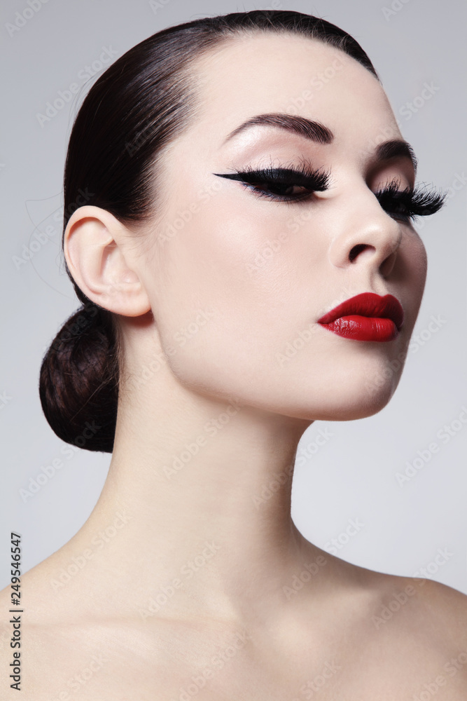 Portrait of young beautiful woman with red lips and cat eye make-up