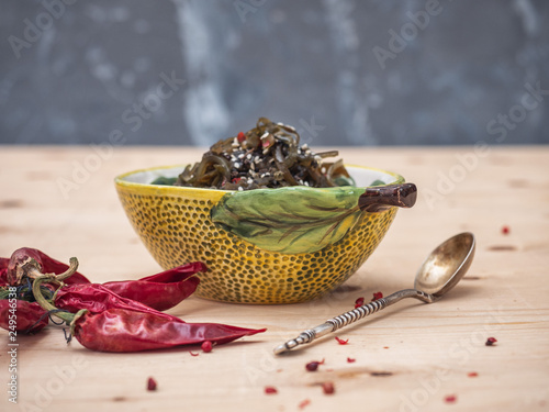 Vegetarian light salad with seaweed and sesame in a ceramic decorative salad bowl, shot from the side. photo