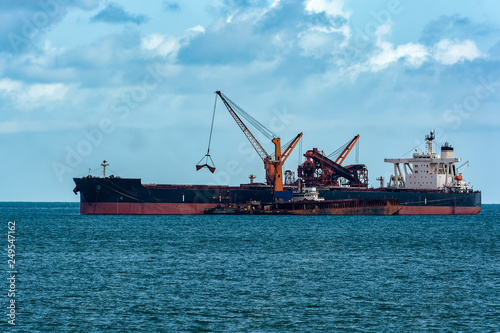 Loading ocean-going bulk carrier ship with Bauxite aluminum ore from the mini bulk carrier (feeder) vessel at offshore Kamsar port, Guinea, West Africa. © Igor Groshev