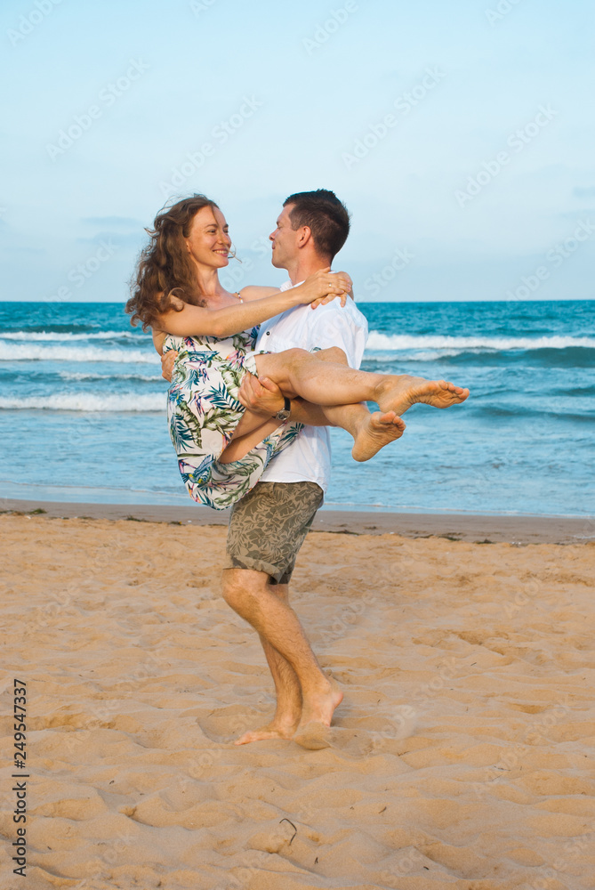 Very happy couple enjoy each other during sunset on the beach. Man holding woman on hands. Very happy couple enjoy each other during sunset on the beach. Man holding woman on hands.