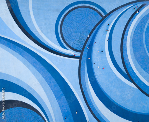 Aerial Drone View of People walking over a Circular Swirl Patterned Blue Floor