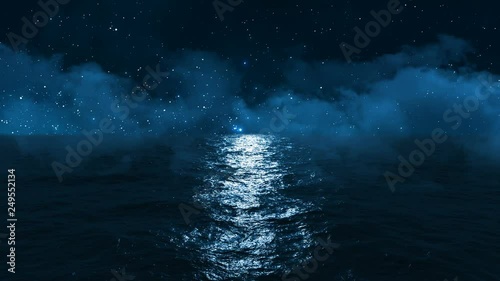 dark blue ocean with moonlight reflected in it against the starry sky and clouds passing above it photo