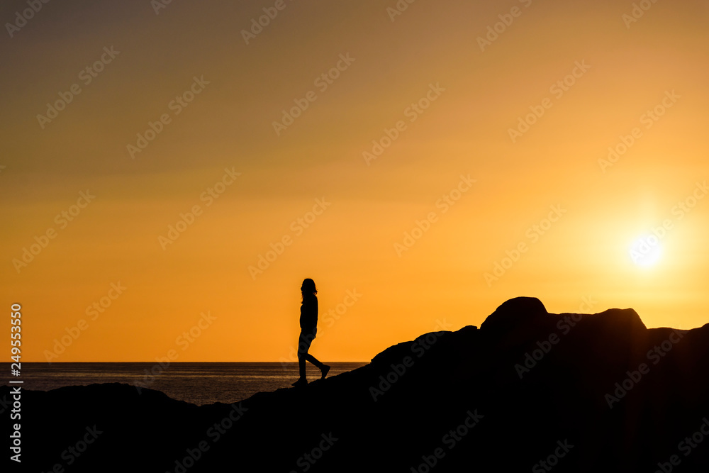Silhouette Person Standing On Cliff Against Orange Sky