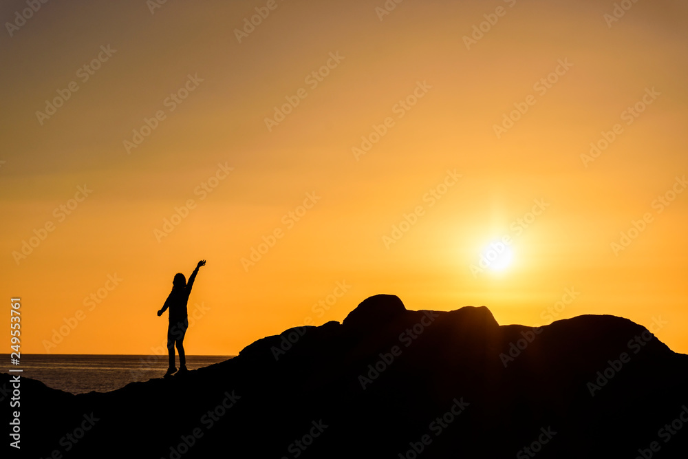 Silhouette Person Standing On Cliff Against Orange Sky