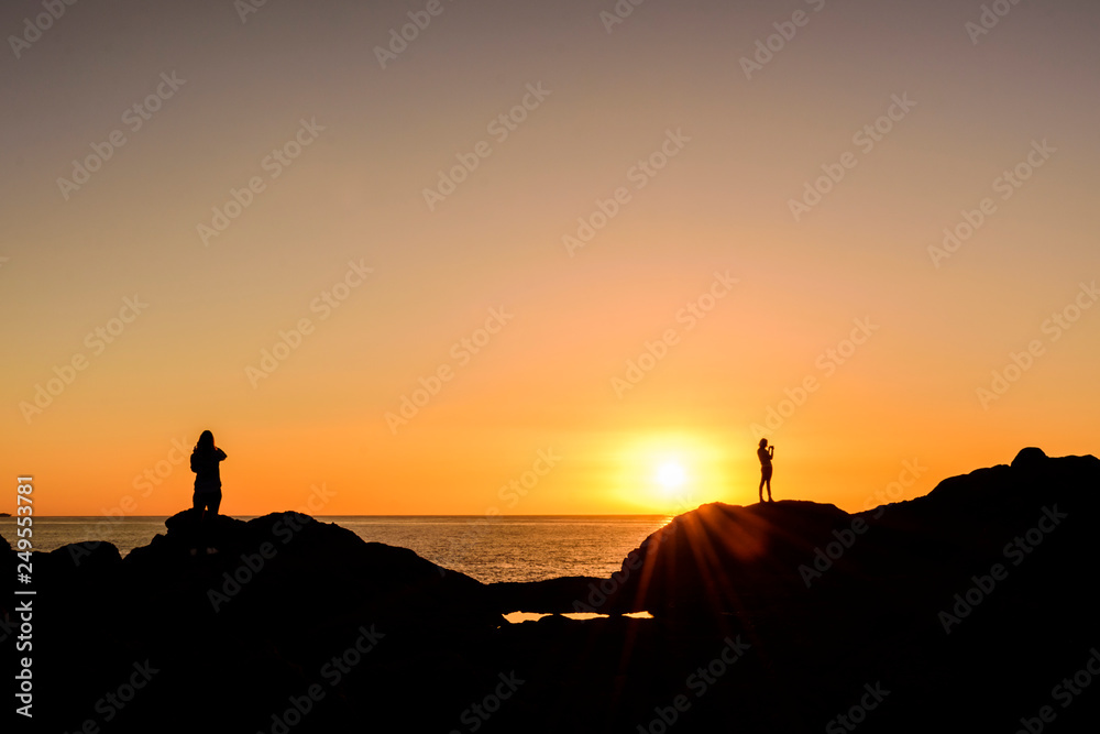 Silhouette People Standing On Rock By Sea Against Clear Sky During Sunset