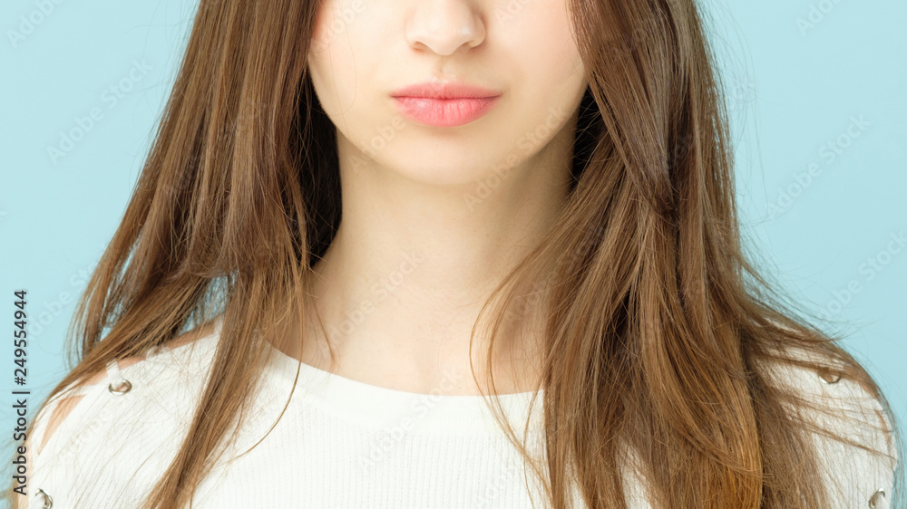 Female plumpy lips. Beauty concept. Girl with long brown hair and clean fresh skin looking toward camera. Female plumpy lips. Beauty concept. Girl with long brown hair and clean fresh skin looking toward camera.