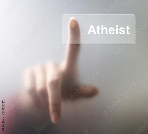 atheist button. Woman finger pressing a glass atheist button on grey background photo
