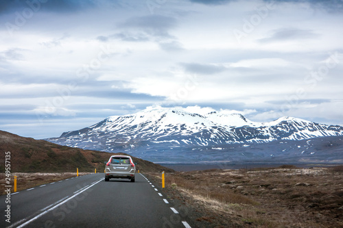 Schilderij op canvas The car rides on the highway with a beautiful view of the sky and snow-covered m