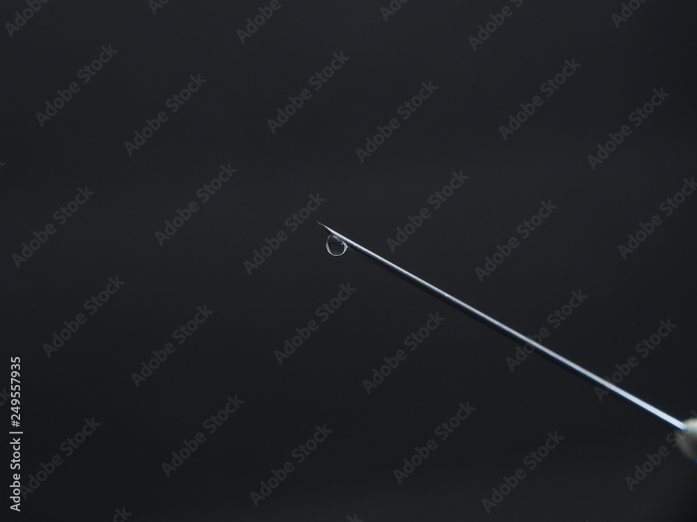 A drop of medicine on the end of a medical syringe needle. A drop of medicine on the end of a medical syringe needle.