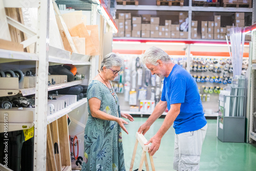 Aged couple choosing and looking stuffs at the hardware market store in the city - people love to build and repair at home - couple real lifestyle