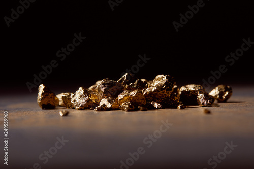 unwrought golden stones at dark on marble table and black background