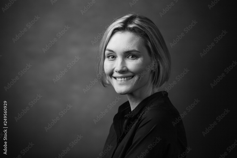 Black and white portrait of a beautiful smiling woman on a dark background Black and white portrait of a beautiful smiling woman on a dark background