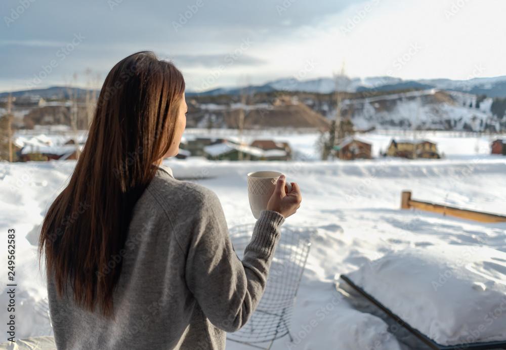 Woman drinking hot beverage in mountains during winter