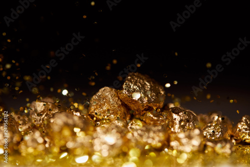 selective focus of golden stones on sparkling surface and black background