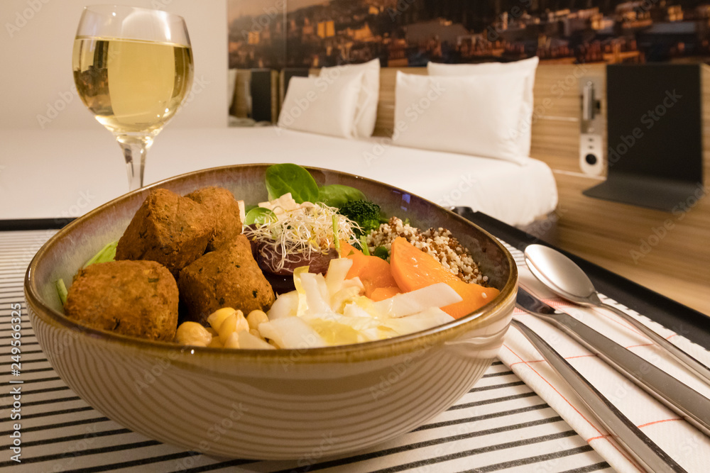 Hotel Room service: vegan meal and white wine with the bed in the backgroud Hotel Room service: vegan meal and white wine with the bed in the backgroud