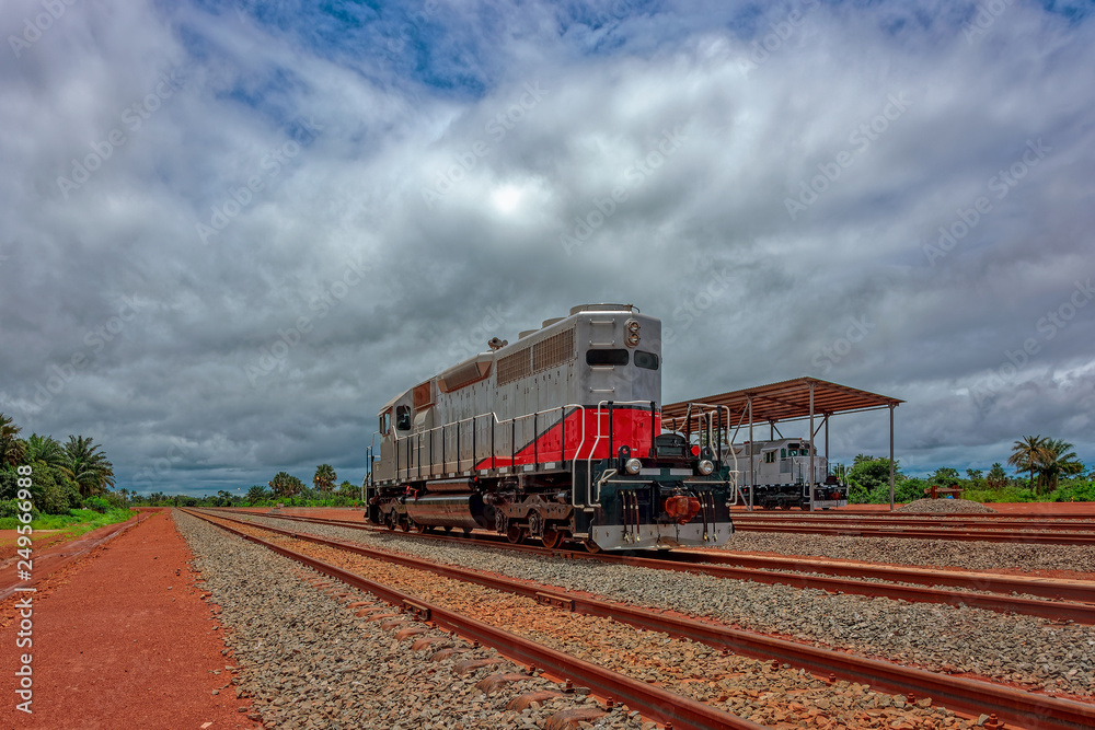 Freight diesel locomotive parked on train tracks at the end of the railway line built for bauxite ore transshipment. Guinea, Africa.