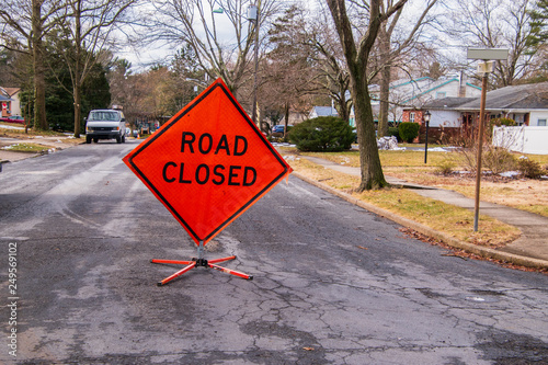 Orange diamond shaped road closure sign on road in a neighborhood near a house. photo