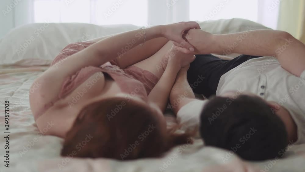 Young couples on bed playing with hands and holding hands together. Lovers happy together. Leisure of young family. Tender relationship of a young couple.