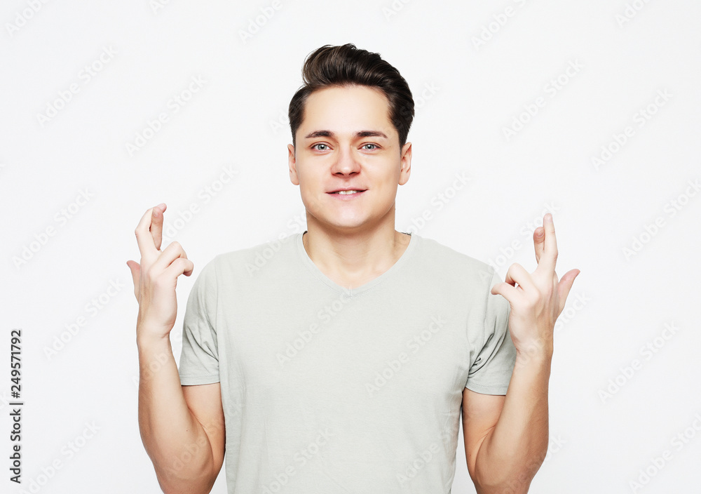 Portrait of charming caucasian man raising hands with crossed fingers and smiling Portrait of charming caucasian man raising hands with crossed fingers and smiling