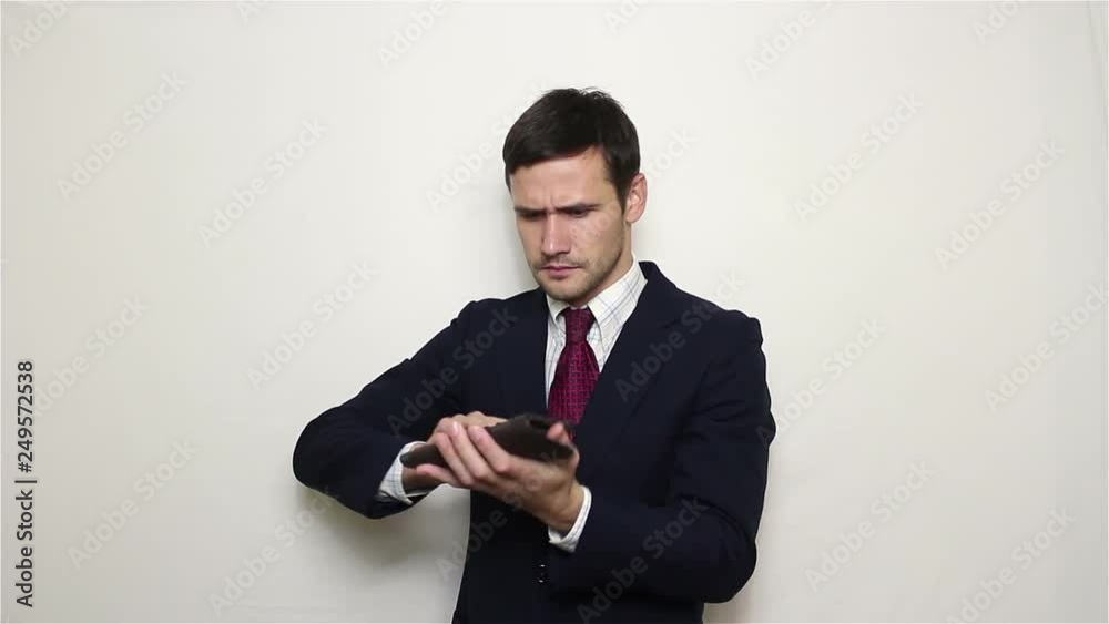 Young handsome businessman shakes his wallet in search of money.Portrait on white background