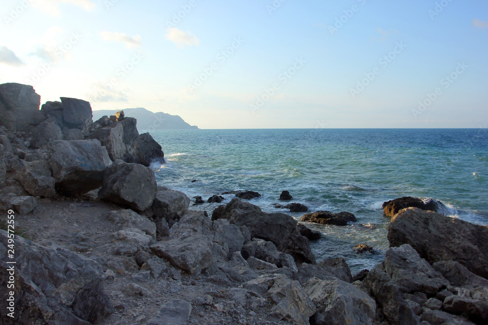beautiful picturesque wild Black sea coast with big dark boulders and rocks in blue sea water beautiful picturesque wild Black sea coast with big dark boulders and rocks in blue sea water