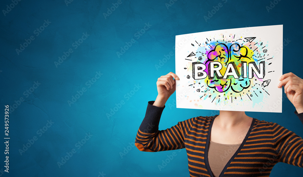 Young person holding white paper in front of her head with colorful brain concept
Young person holding white paper in front of her head with colorful brain concept