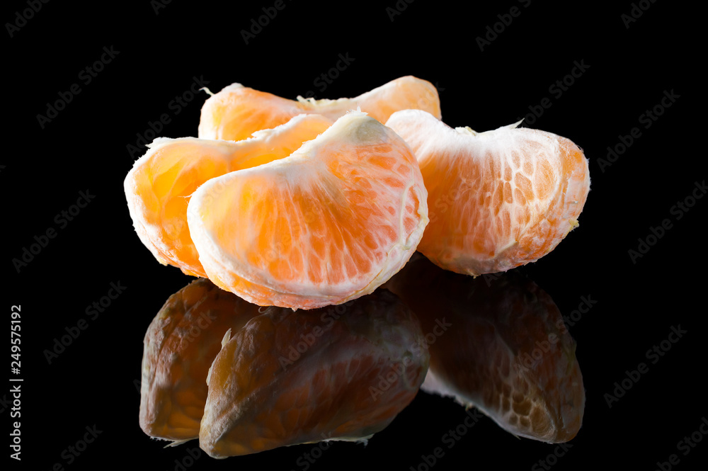Tangerines or mandarins slices on black reflective background. Tangerines or mandarins slices on black reflective background.